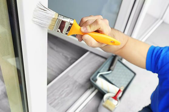 Person lackiert den Rahmen eines Fensters